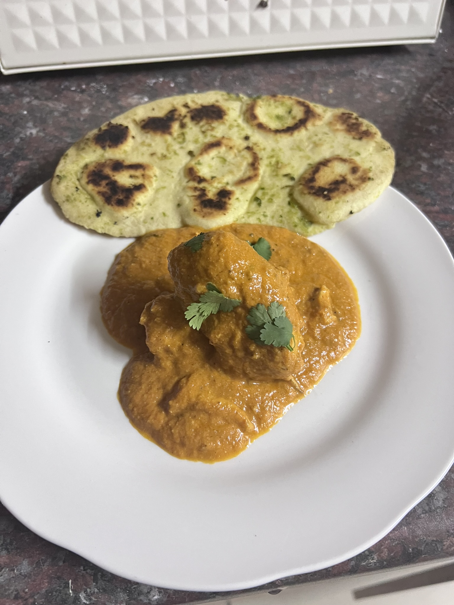 Butter chicken, plated with naan and rice