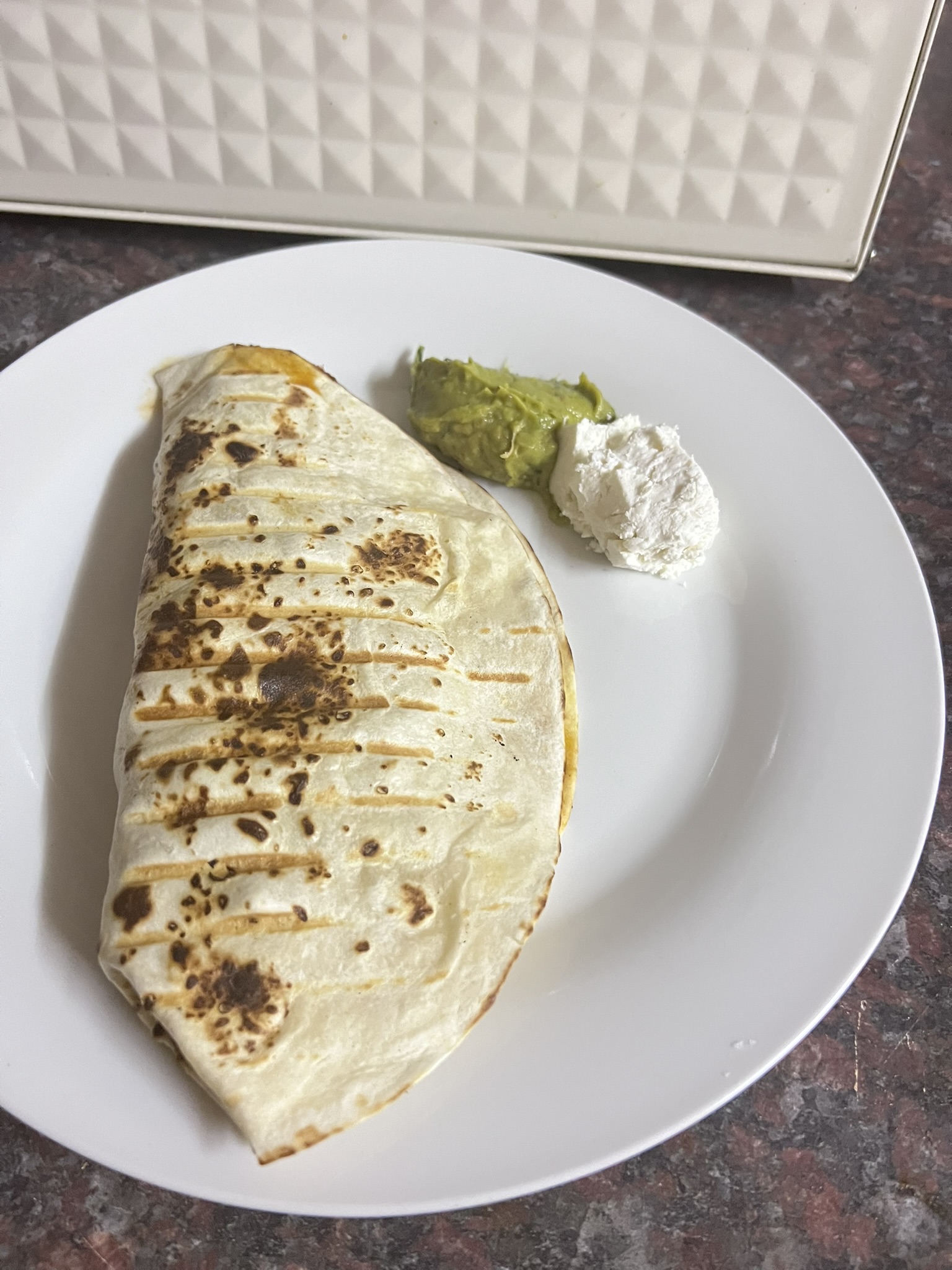 Folded steak fajita with griddle marks, guacamole and sour cream on the side